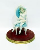 Lladro figure of a harlequin boy seated on a chair holding a cat, on circular base 27cm highNo