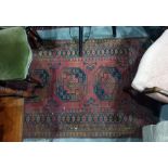 Red ground Eastern floor rug with three central elephant foot medallions, decorated in black,