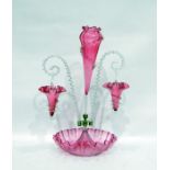 Cranberry glass epergne, the central pink ground flute flanked by hanging baskets, on a handkerchief