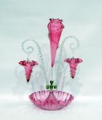 Cranberry glass epergne, the central pink ground flute flanked by hanging baskets, on a handkerchief