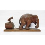 Carved hardwood model of a man working an elephant, 45cm long