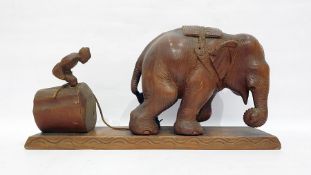 Carved hardwood model of a man working an elephant, 45cm long