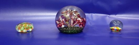 Decorative paperweight of white and cranberry flowerburst design and two smaller millefiori