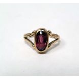 Gold ring set with a central oval garnet, with split shoulders (unmarked) (with damage)