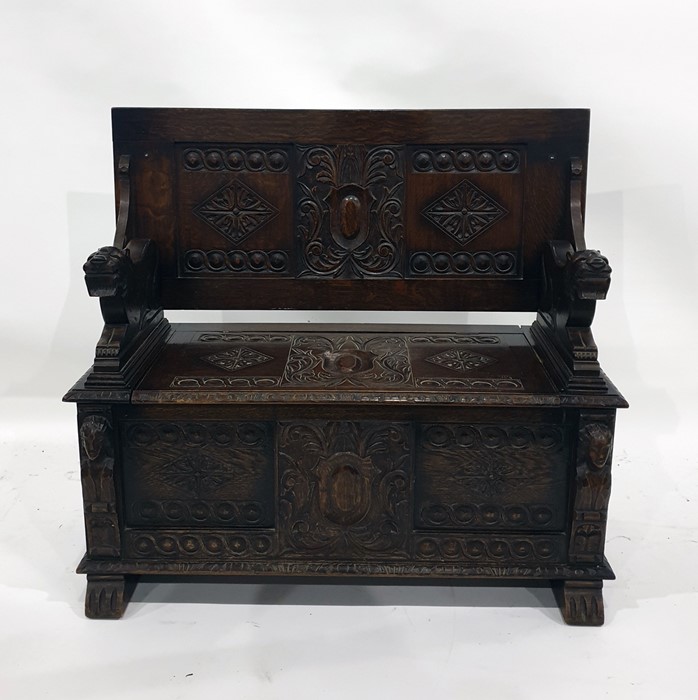 20th century oak monk's type bench with carved back, seat and front panels, the arms terminating