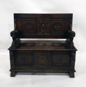 20th century oak monk's type bench with carved back, seat and front panels, the arms terminating