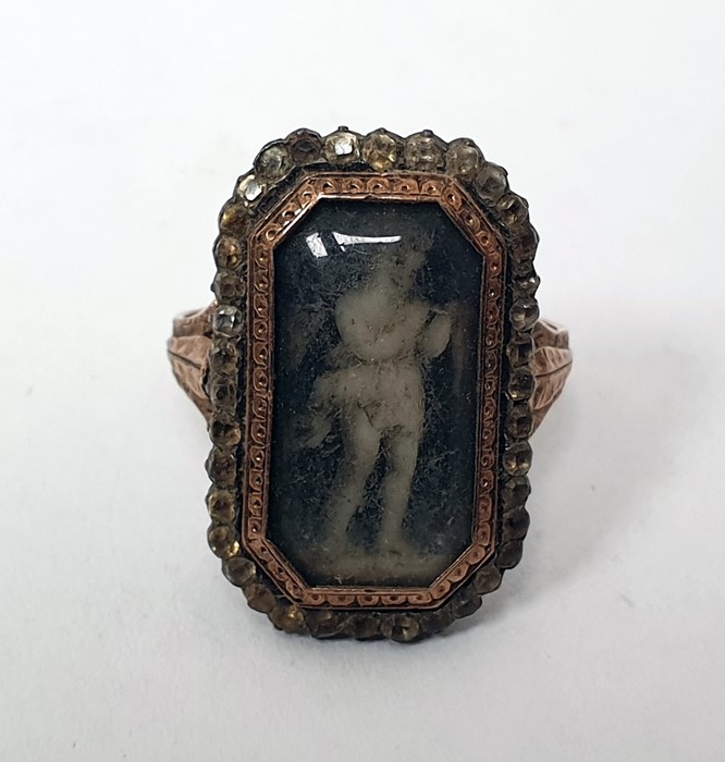 Georgian ring of shaped rectangular form, set with an enamel of a child under a glazed cover,