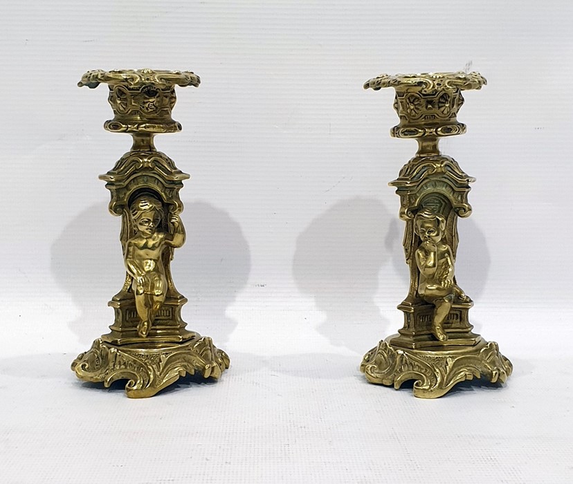 Pair of brass candlesticks, the stems modelled with seated children and on scrolling circular bases,