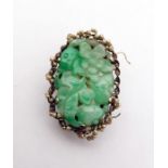 Chinese clip set with a central oval carved jade panel depicting flowers and foliage, the mount