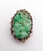 Chinese clip set with a central oval carved jade panel depicting flowers and foliage, the mount