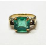 18ct gold ring set with large square cut emerald to the centre, the shoulders with settings for