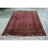 Eastern rug on red ground with four rows of 14 elephant foot guls, 273cm x 203cm