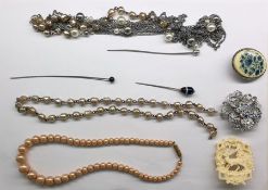 Assorted costume jewellery including agate stickpin, faux pearls, brooches, a hammered silver-