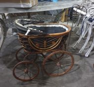 An Edwardian wickerwork dolls' pram, with ceramic push handle and ceramic handles to the folding