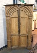 19th century pine corner cabinet with arched top, panelled doors, flanked by applied moulded