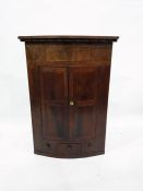 19th century mahogany bowfront wall hanging corner cupboard, the two doors enclosing shelves, with