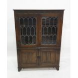 20th century oak cabinet with leaded glazed doors enclosing shelves, above two linenfold decorated