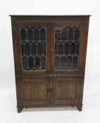 20th century oak cabinet with leaded glazed doors enclosing shelves, above two linenfold decorated