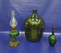 Green glass carboy, a green glass decanter and an oil lamp with metal base and green glass reservoir