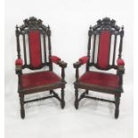 Pair of Victorian carved oak framed armchairs with red upholstered arms and seat