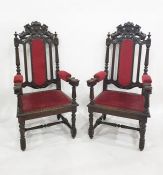 Pair of Victorian carved oak framed armchairs with red upholstered arms and seat