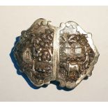 Indian white metal buckle of shaped form, depicting farming scenes in relief, 8cm long