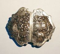 Indian white metal buckle of shaped form, depicting farming scenes in relief, 8cm long