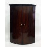 George III mahogany bowfronted wall hanging corner cupboard, the pair of panelled doors with bone