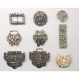 Silver-coloured buckle of elaborate pierced design around a central seated figure, a paste