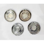 Four Middle Eastern white-coloured metal circular engraved trinket dishes, each inset coin to