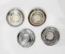 Four Middle Eastern white-coloured metal circular engraved trinket dishes, each inset coin to