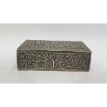 Indian white metal box of rectangular form, the hinged cover decorated with flowers in a leaf