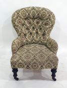Low Victorian nursing chair with a cream ground patterned upholstery, on mahogany turned legs to