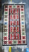 Cream ground rug with long red ground lozenge, in creams, greens, reds, blacks, taupes and blues,