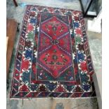 Persian style wool rug, the red ground with two lozenge medallions and geometric border, 192cm x