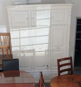 White painted pine cupboard, the ogee moulded cornice above three door top box, three wardrobe