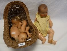 Various composite doll parts including one complete doll but all AF within a wicker dolls rocking