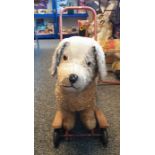Child's push and ride-along toy in form of dog, mounted on tubular red painted frame and four wheels