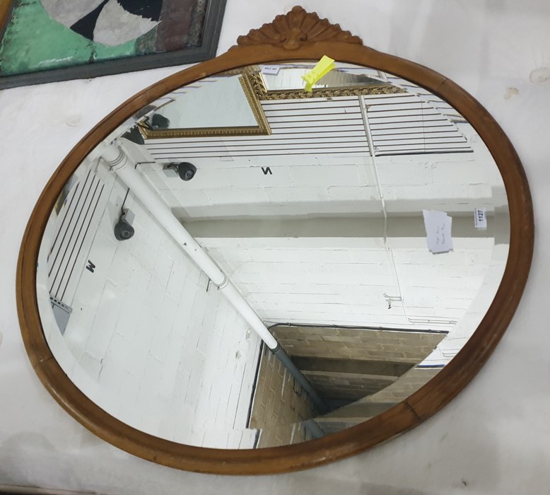 An oval bevel edged wall mirror in a carved wood frame