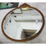 An oval bevel edged wall mirror in a carved wood frame