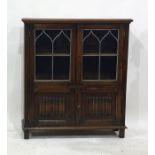 A 20th century oak cabinet with leaded glazed doors above two linen-fold doors, 85cm x 107.5cm