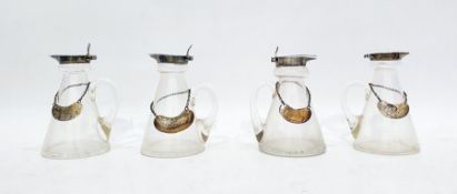 Four similar miniature glass jugs with silver rims and lids, each bearing silver bottle labels marke