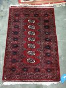 Red ground Eastern rug with seven central elephant foot guls, on a stepped border, 123cm x 80cm