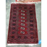 Red ground Eastern rug with seven central elephant foot guls, on a stepped border, 123cm x 80cm