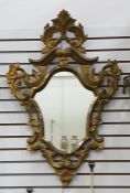 Shield-shaped, carved wood gilt-framed wall mirror with foliate and floral scroll border