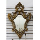 Shield-shaped, carved wood gilt-framed wall mirror with foliate and floral scroll border