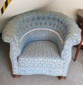 A late 19th/early 20th century button-back tub chair in a blue ground patterned upholstery, turned