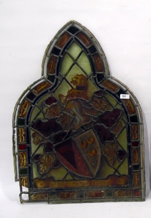 Antique stained glass arched window panel with armorial decoration; the shield decorated with