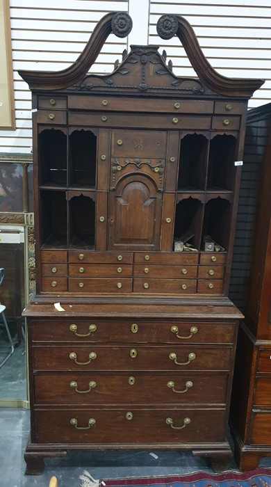 A possibly continental mahogany secretaire, the swan neck pediment terminating in carved foliate