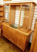 Modern light elm Ercol dresser, the shaped top above central open glass shelves flanked by glass